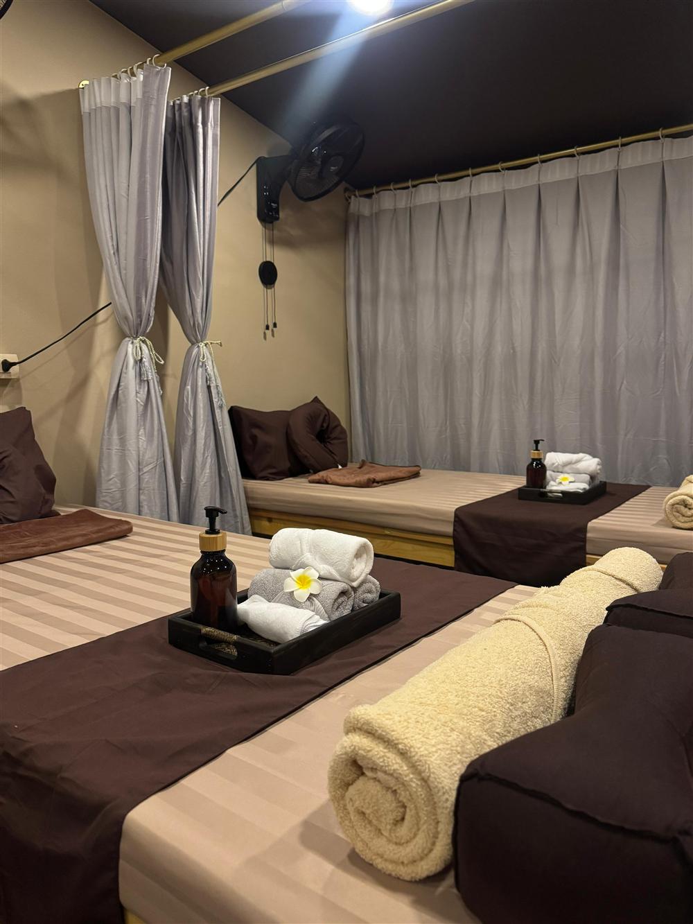Two treatment beds prepared side by side with towels and frangipani flowers